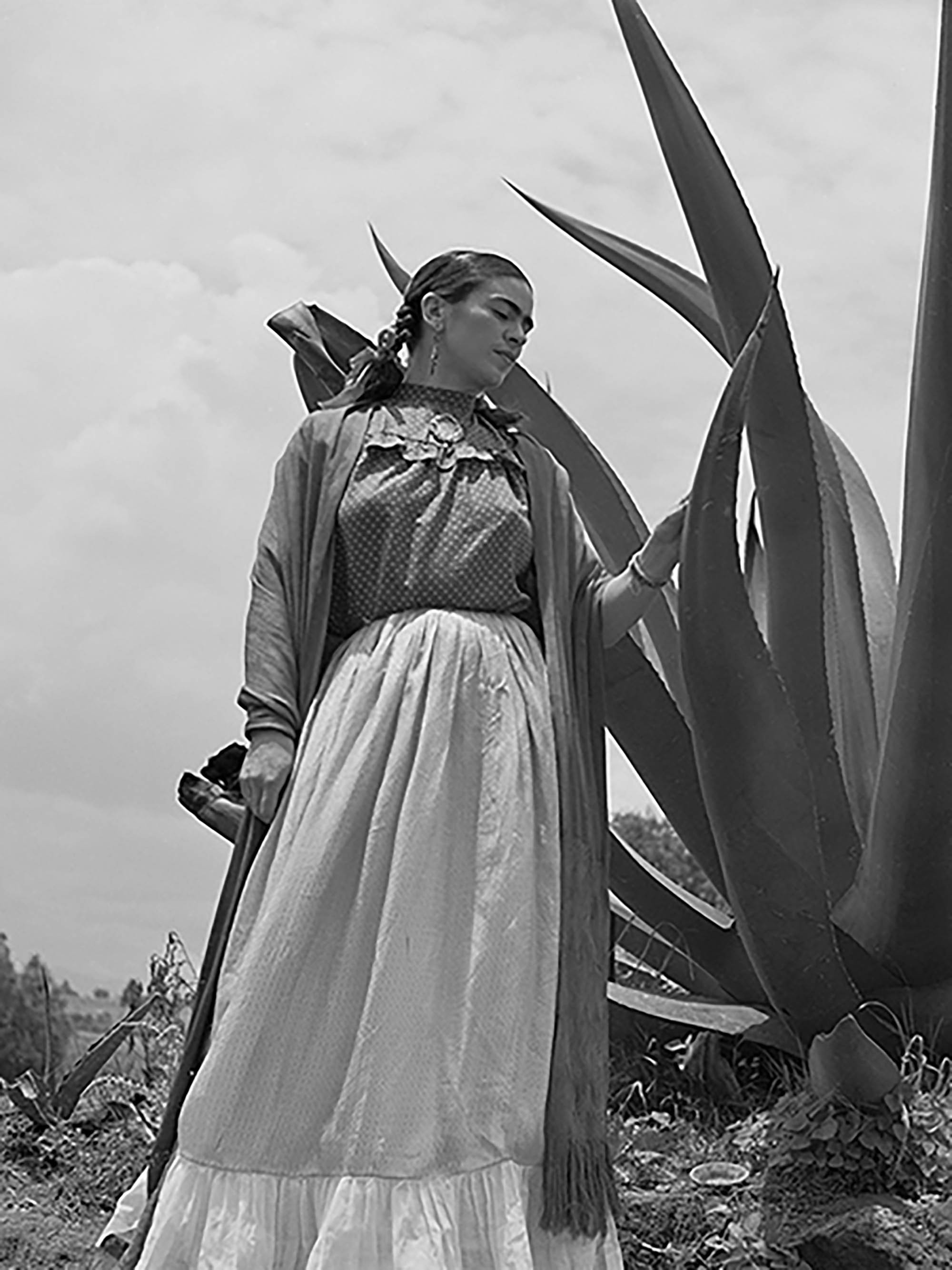 Frida Kahlo de pie junto a una planta de agave